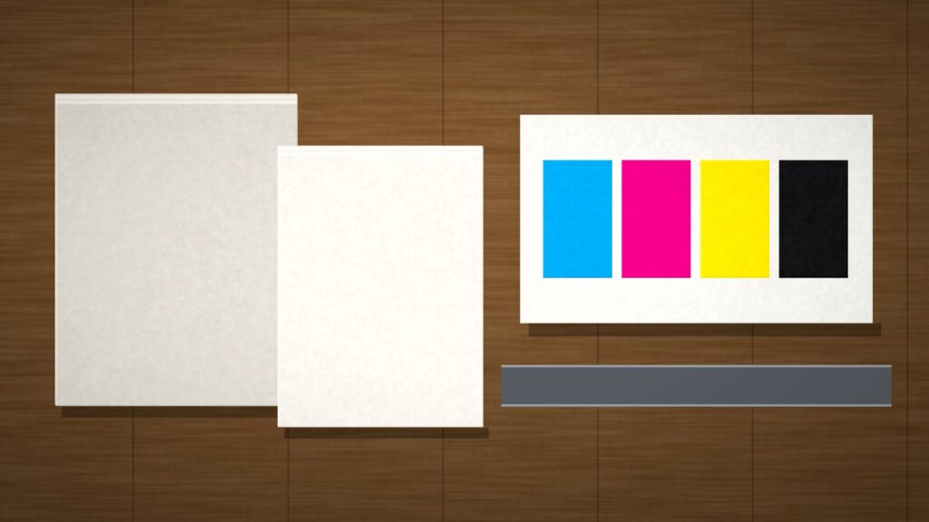Stacks of unprinted paper and CMYK color blocks on a commercial print-shop production table, no people or text